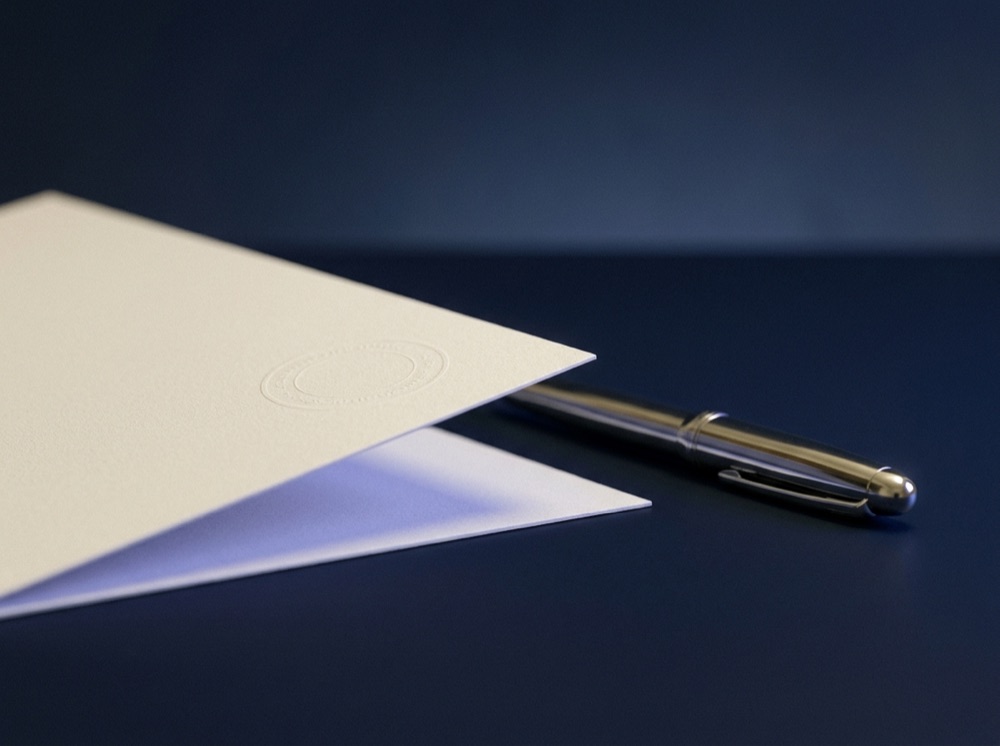 A sealed regulatory document and pen on a dark surface