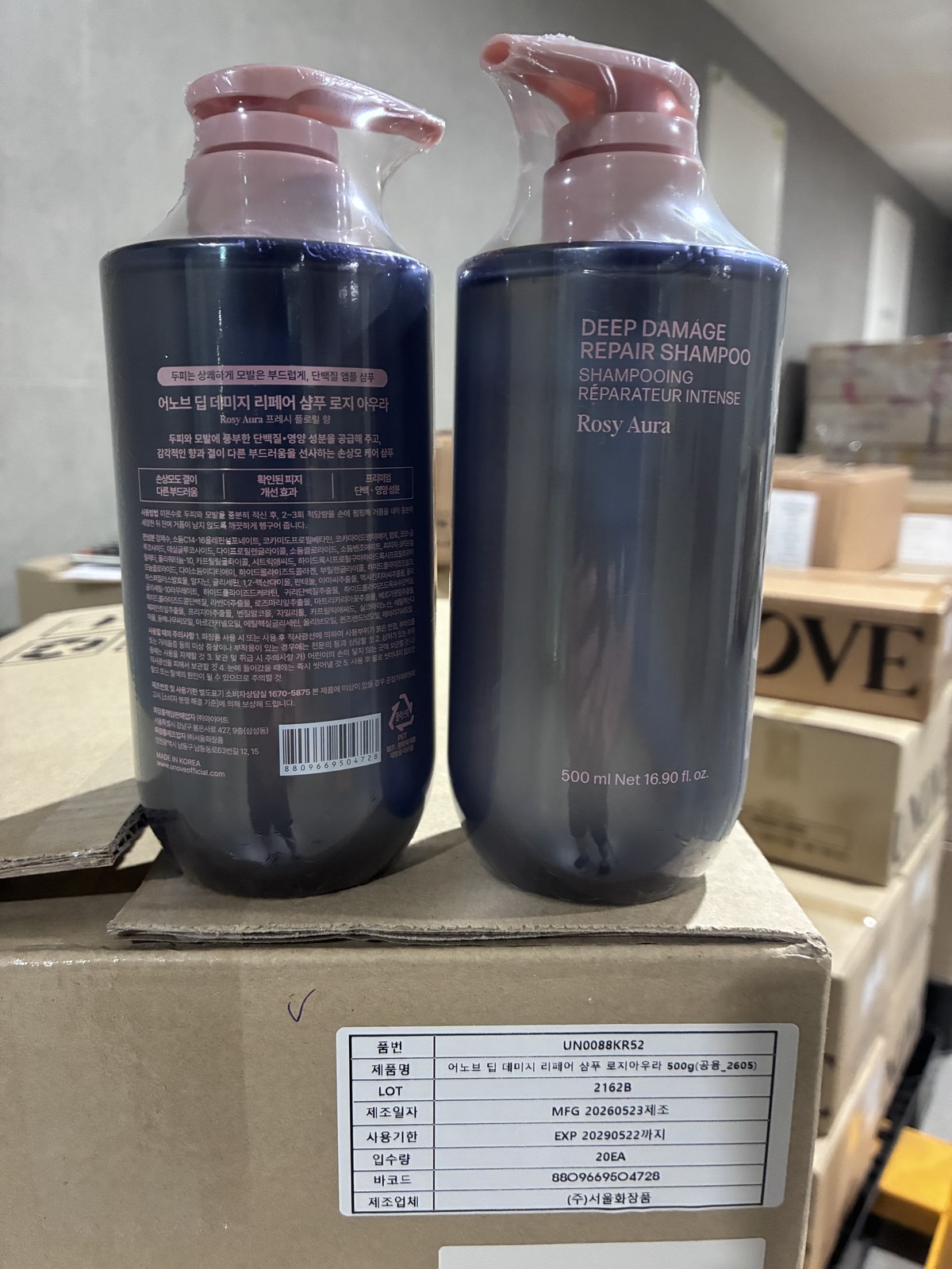 Korean shampoo bottles above a master carton spec label showing item code, lot, manufacture date, expiry, units per carton, barcode and manufacturer